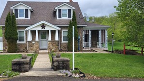 A two-story house with a stone facade, a front porch, and a satellite dish. - Quiet Space with Spacious Yard for Parking in Nice Community  (East Millsboro)