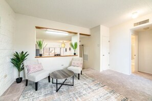 A modern living room with a sofa, a round coffee table, and two potted plants.