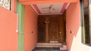 A narrow entrance with a ceiling fan, a wooden door with intricate carvings, and a small sign above the door. - Galaxy Lodge  (Islamabad)