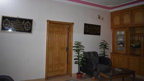 A living room with a ceiling fan, wooden door, and two potted plants. - Galaxy Lodge  (Islamabad)