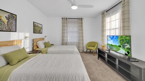 Ein Hotelzimmer mit zwei Betten, einem Deckenventilator, einem Fernseher und einem Fenster mit Vorhängen.