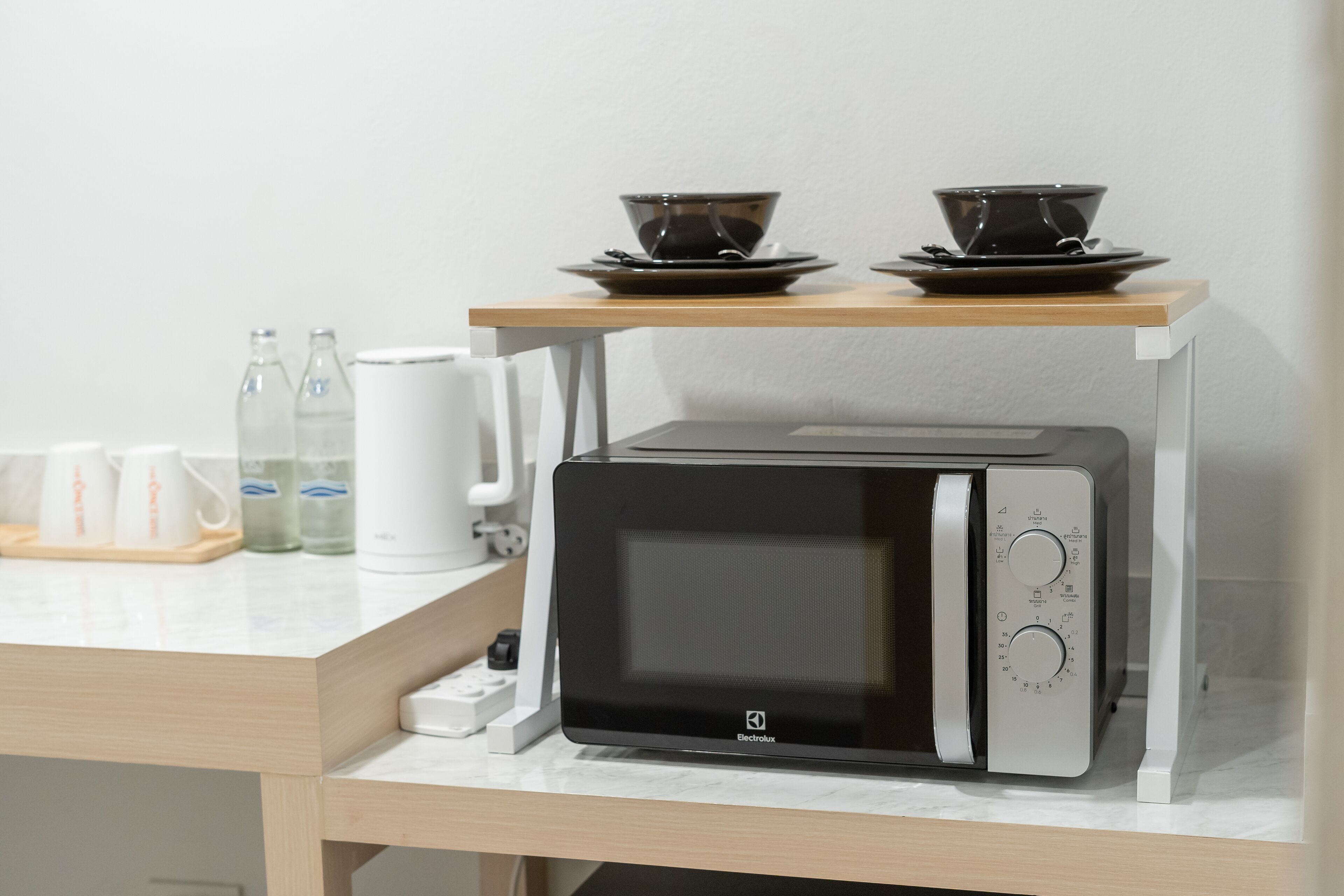 A compact microwave oven with a digital display, a control panel with multiple settings, and a small water bottle on the counter.