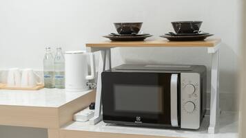 A compact microwave oven with a digital display, a control panel with multiple settings, and a small water bottle on the counter.