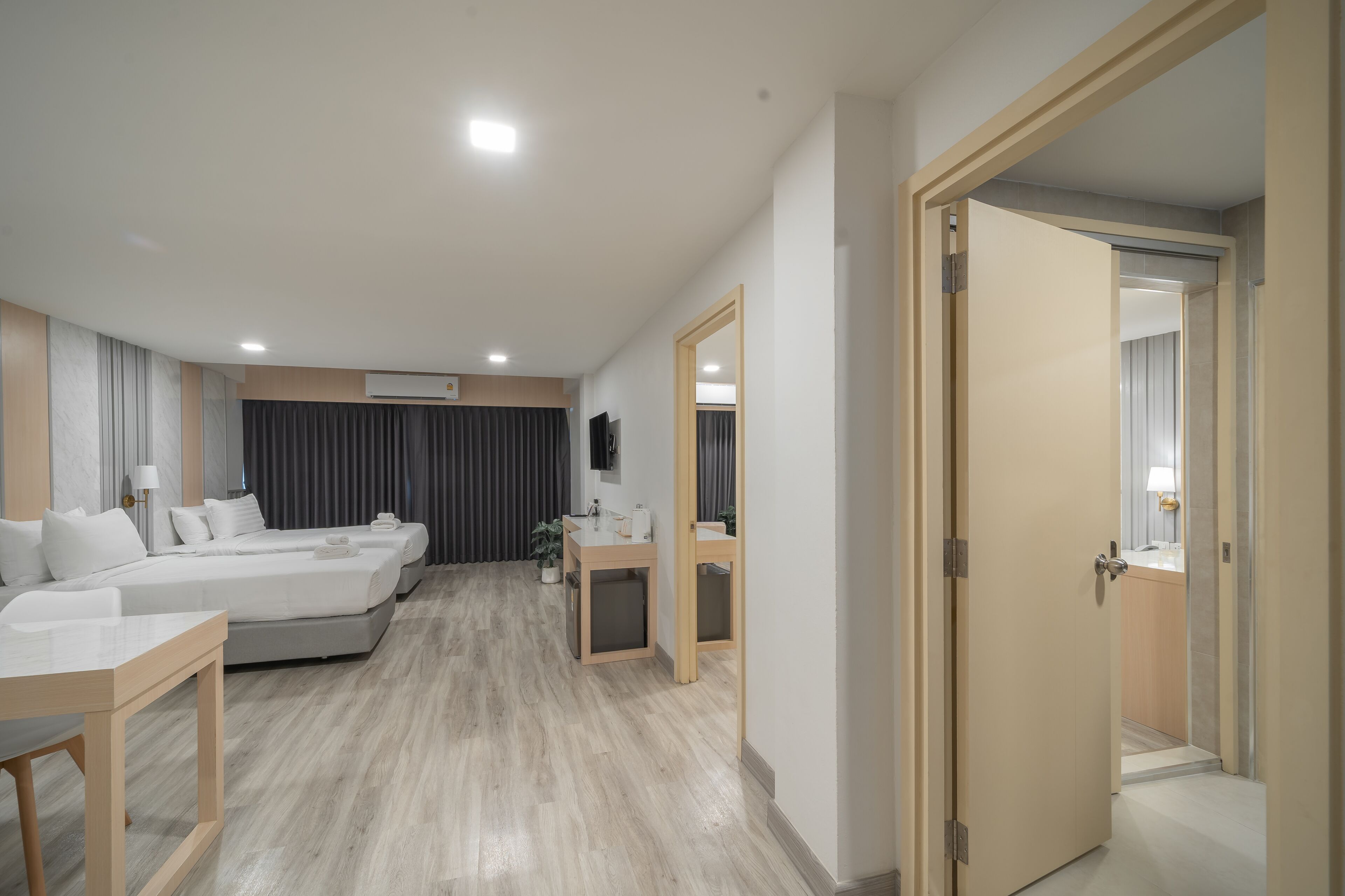 A modern hotel room with a large bed, a desk, a small bathroom, and a TV.