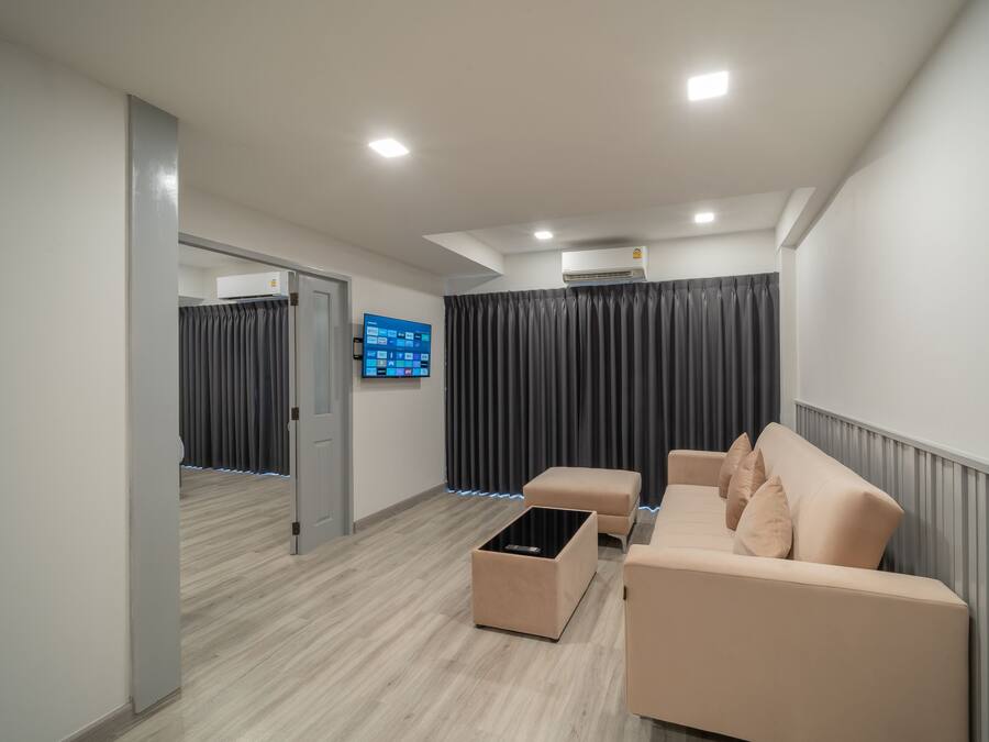 A modern living room with a beige sofa, a coffee table, and a flat-screen TV mounted on the wall.