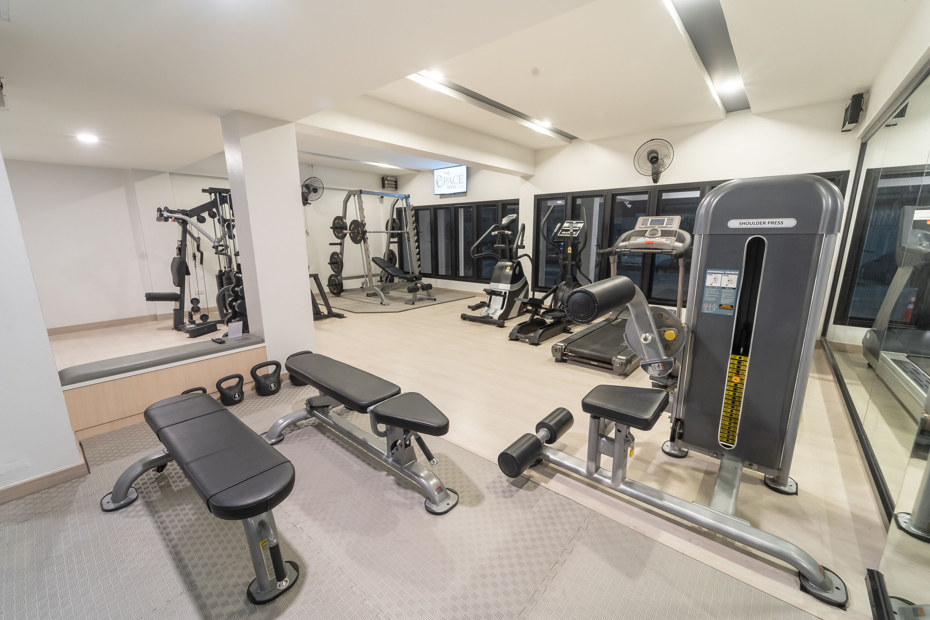 Un gimnasio con bancos, mancuernas y máquinas de pesas.