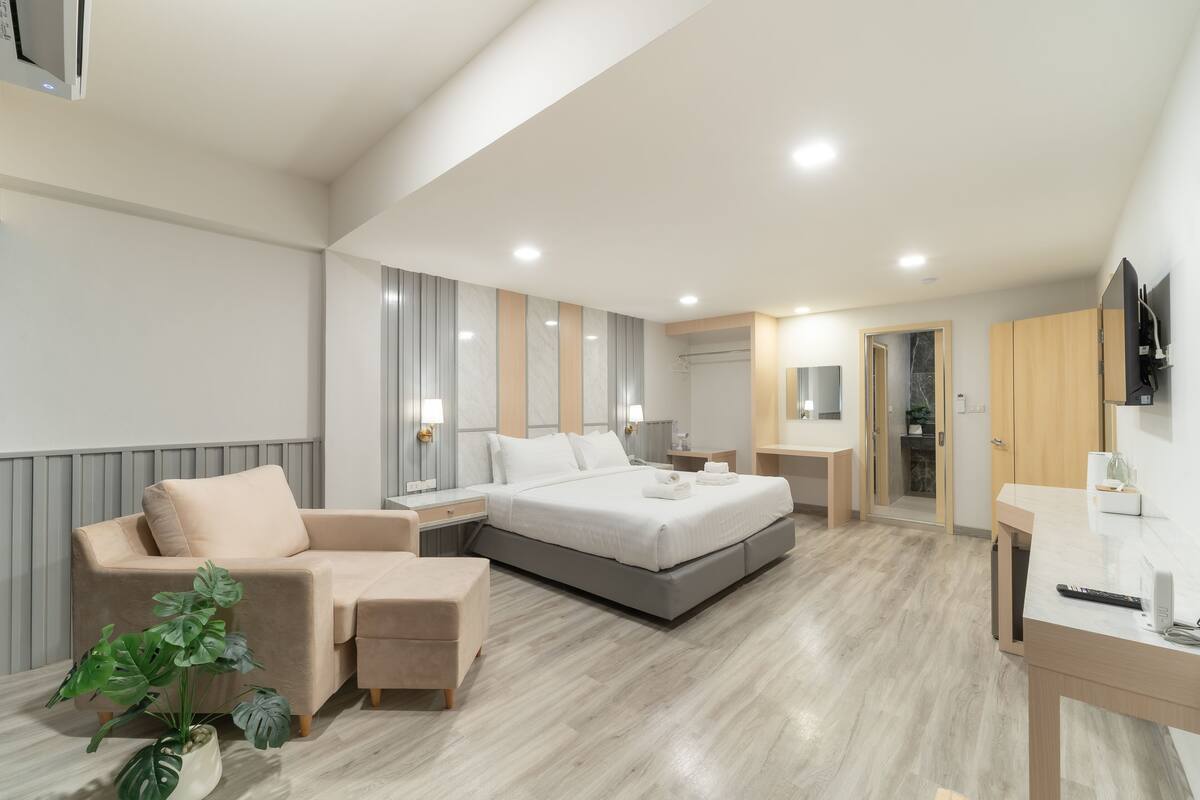 Une chambre d’hôtel moderne, équipée d’un lit, d’un canapé, d’un bureau et d’une plante.