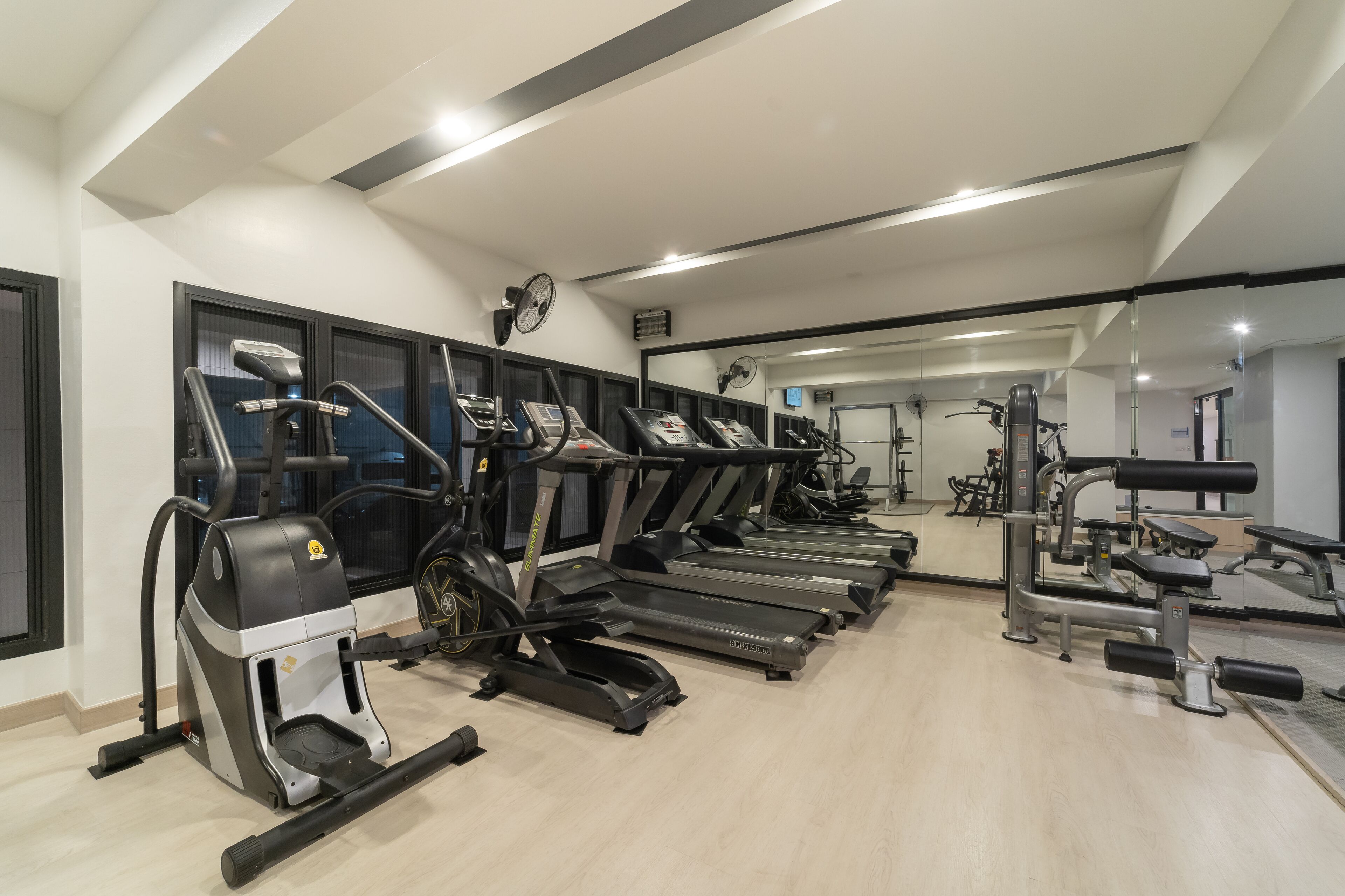 Un gimnasio con cintas de correr, elípticas y máquinas de pesas.