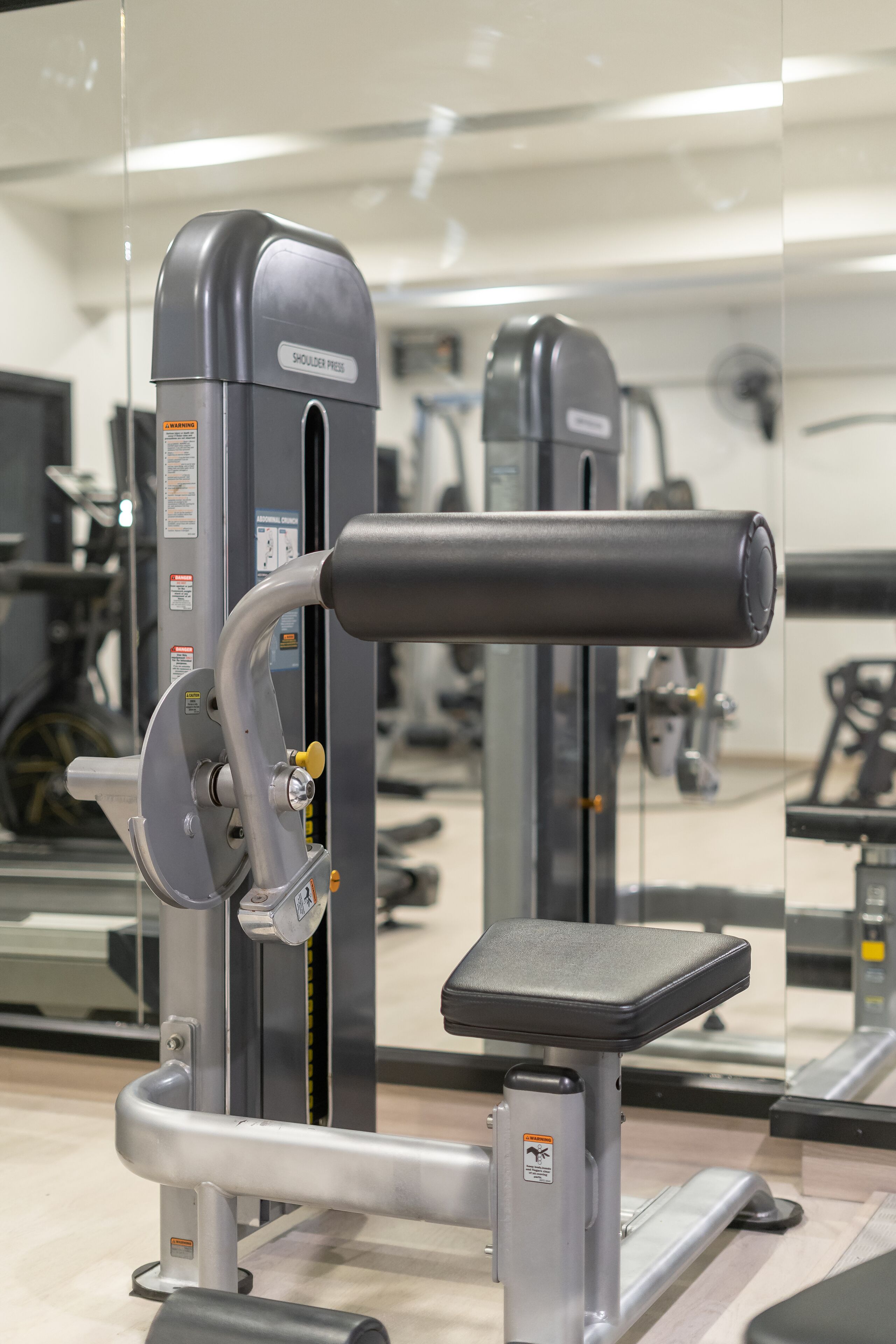 A gym with exercise equipment, including a shoulder press machine and a bench.