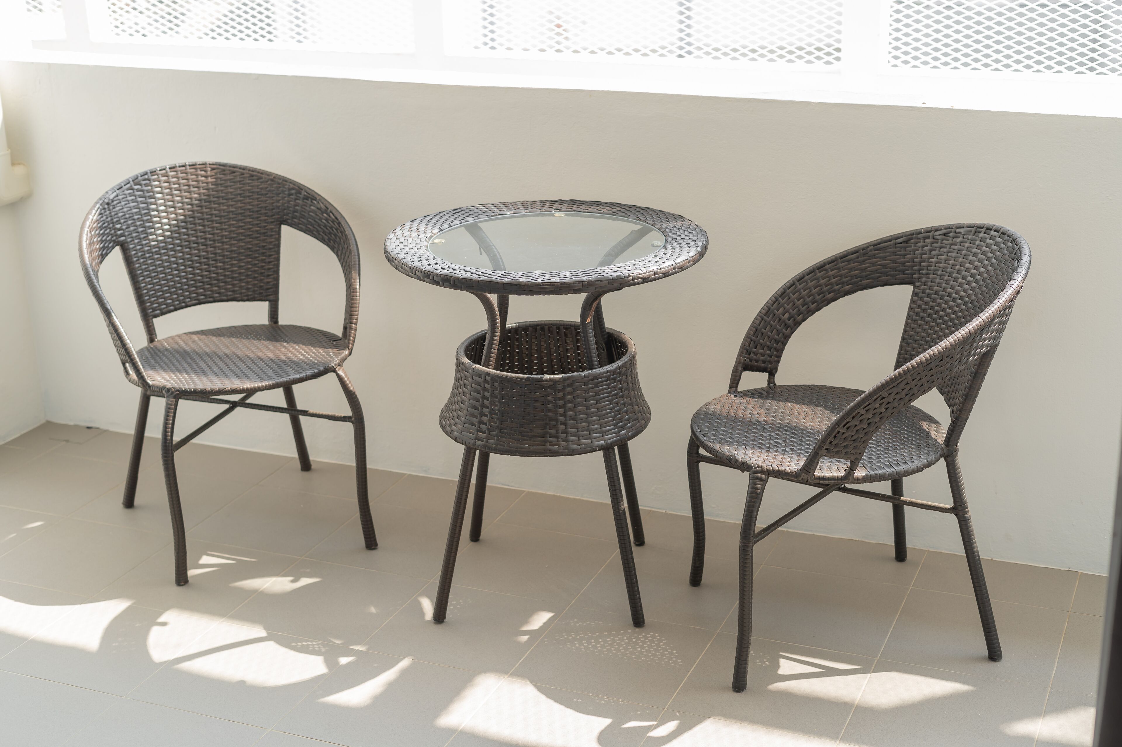A small outdoor seating area with wicker chairs and a glass table.