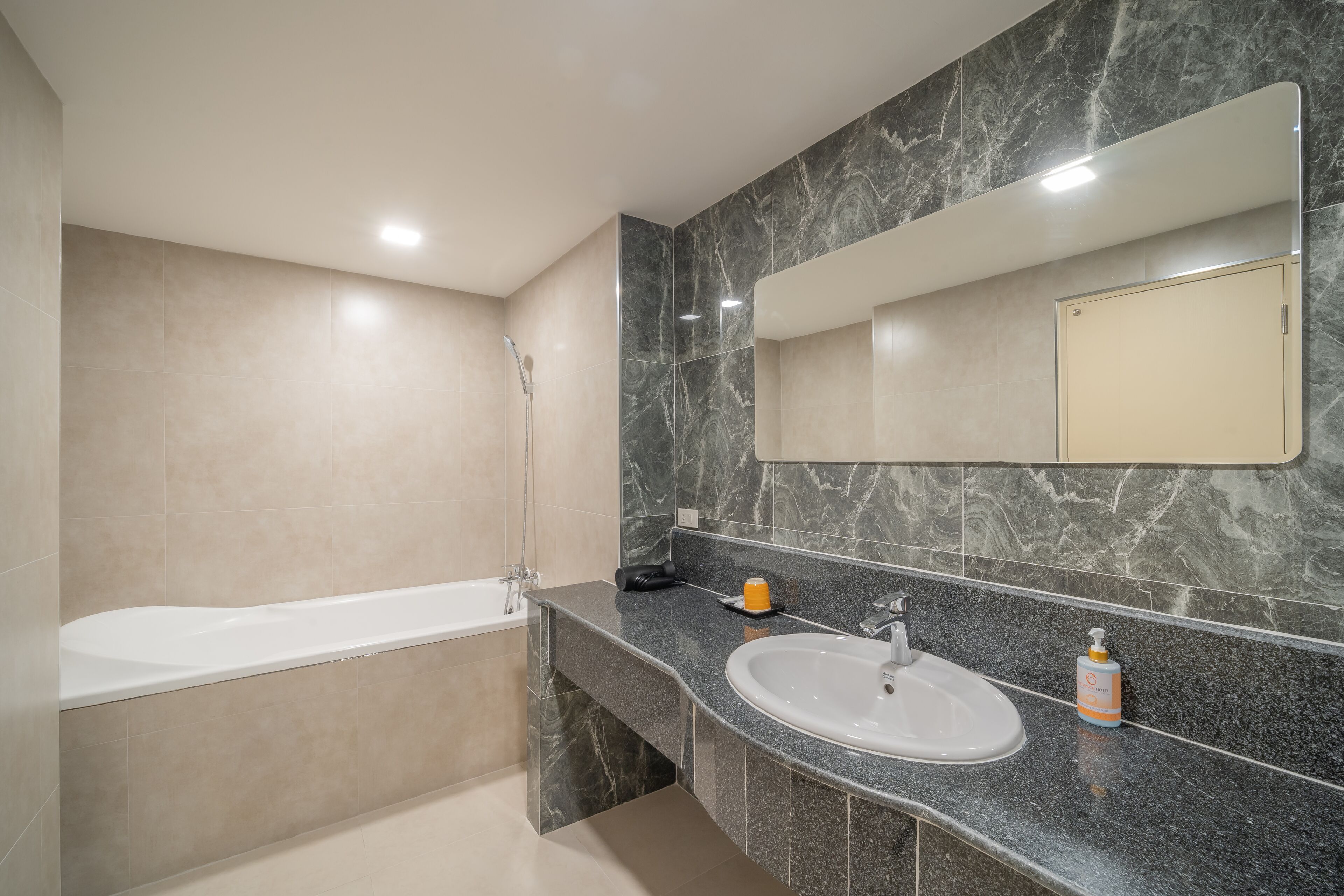 A modern bathroom with a bathtub, a sink, and a large mirror.
