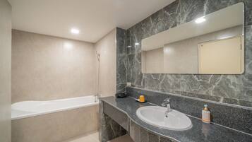 A modern bathroom with a bathtub, a sink, and a large mirror.