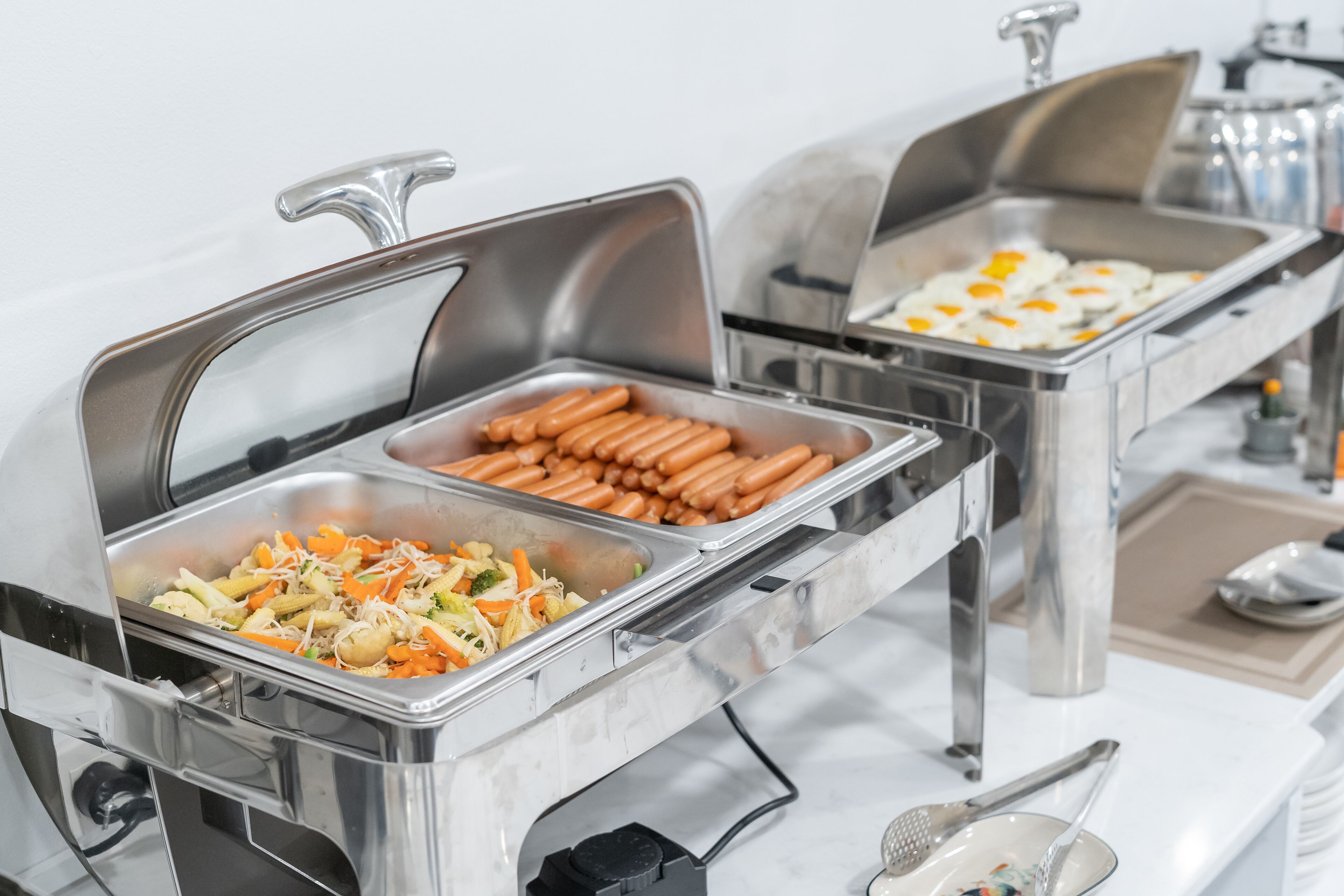 A buffet with various food options including hot dogs, eggs, and a salad.