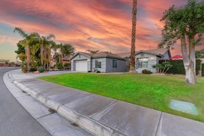 A residential neighborhood with houses, a well-maintained lawn, and a curved sidewalk.