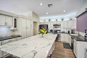 A modern kitchen with white cabinetry, a marble island, and a central island with yellow flowers.