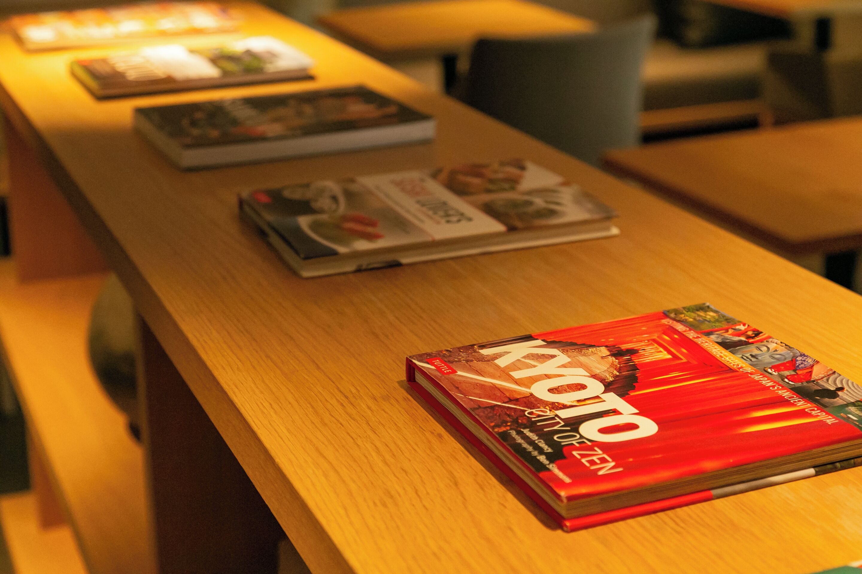 A wooden table with magazines and a book titled "KYOTO OPEN".