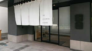 A building entrance with a white banner reading "THE GENERAL KYOTO" and a sign indicating "THE GENERAL KYOTO" on the wall.