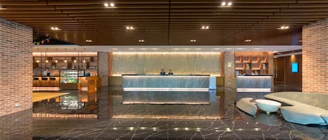 A lobby with a reception desk, seating area, and a bar.