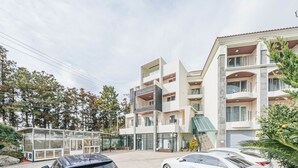 A modern multi-story building with a glass facade, a covered entrance, and a parking area with cars. - Today Seogwipo (Seogwipo)