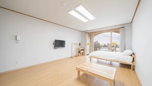 A bedroom with a bed, a wooden bench, a TV, and a window with a view. - Today Seogwipo (Seogwipo)