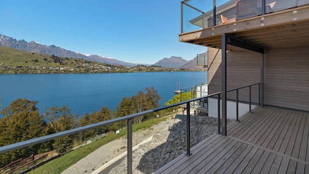 Un edificio moderno con terraza de madera con vistas a un lago y montañas.