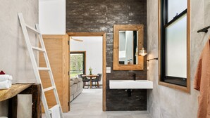 Ein modernes Badezimmer mit einem großen Spiegel, einem weißen Waschbecken und einer Holzleiter.