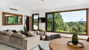 Ein modernes Wohnzimmer mit großem Fenster, Deckenventilator und einem Holzessttisch.