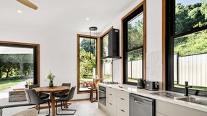 Eine moderne Küche mit großen Fenstern, einem Essbereich und einem eingebauten Geschirrspüler.