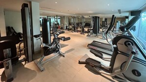 A gym with various exercise equipment including treadmills, stationary bikes, and weight machines. - Stunning Ocean View Studio Apartment (Tambon Rawai)