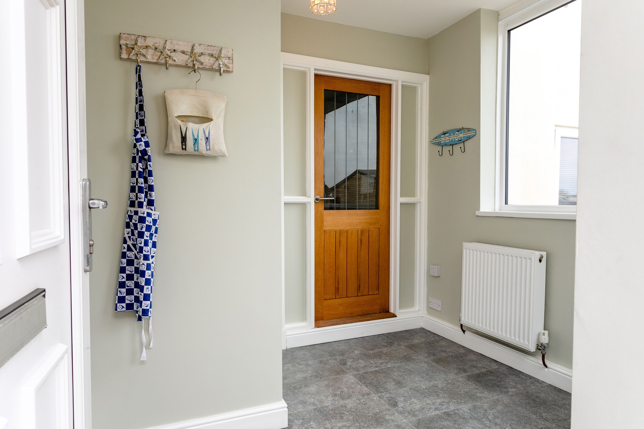 A hallway with a wooden door, a white radiator, and a blue patterned towel hanging on the wall.