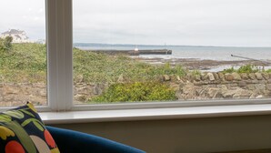 Une chambre avec vue sur une côte rocheuse et un phare.