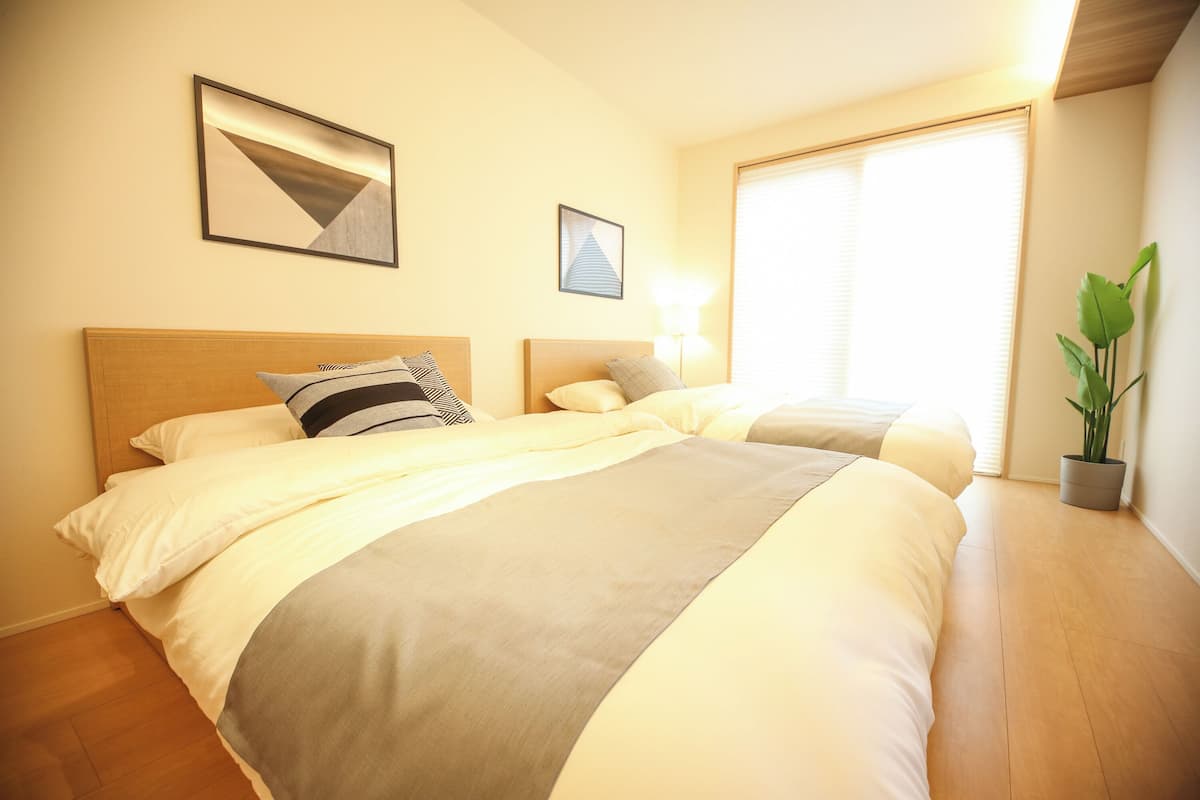 Una habitación de hotel con dos camas, un ventanal grande y una planta en maceta.