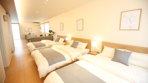 Une chambre d’hôtel avec quatre lits disposés en rangée, un bureau et une grande fenêtre.