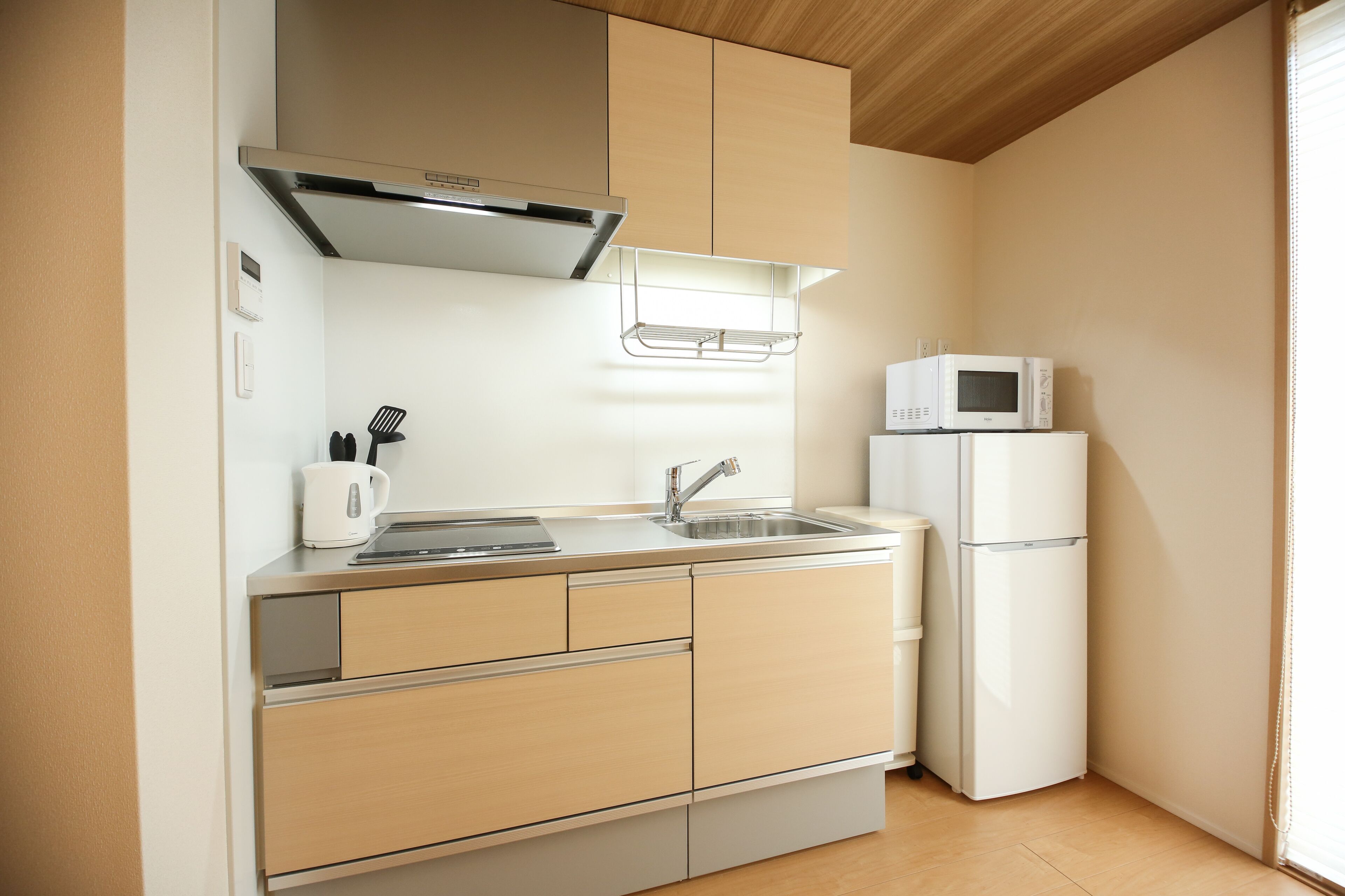 Una cocina compacta con microondas, pileta y muebles de cocina modernos.