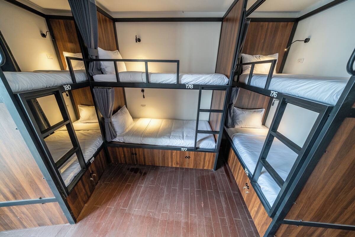 A bunk bed room with wooden flooring and metal railings.