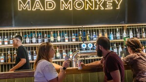 A bar with a neon sign reading "MAD MONKEY" and shelves stocked with various liquor bottles. - Mad Monkey Hanoi - Hostel (Hanoi)