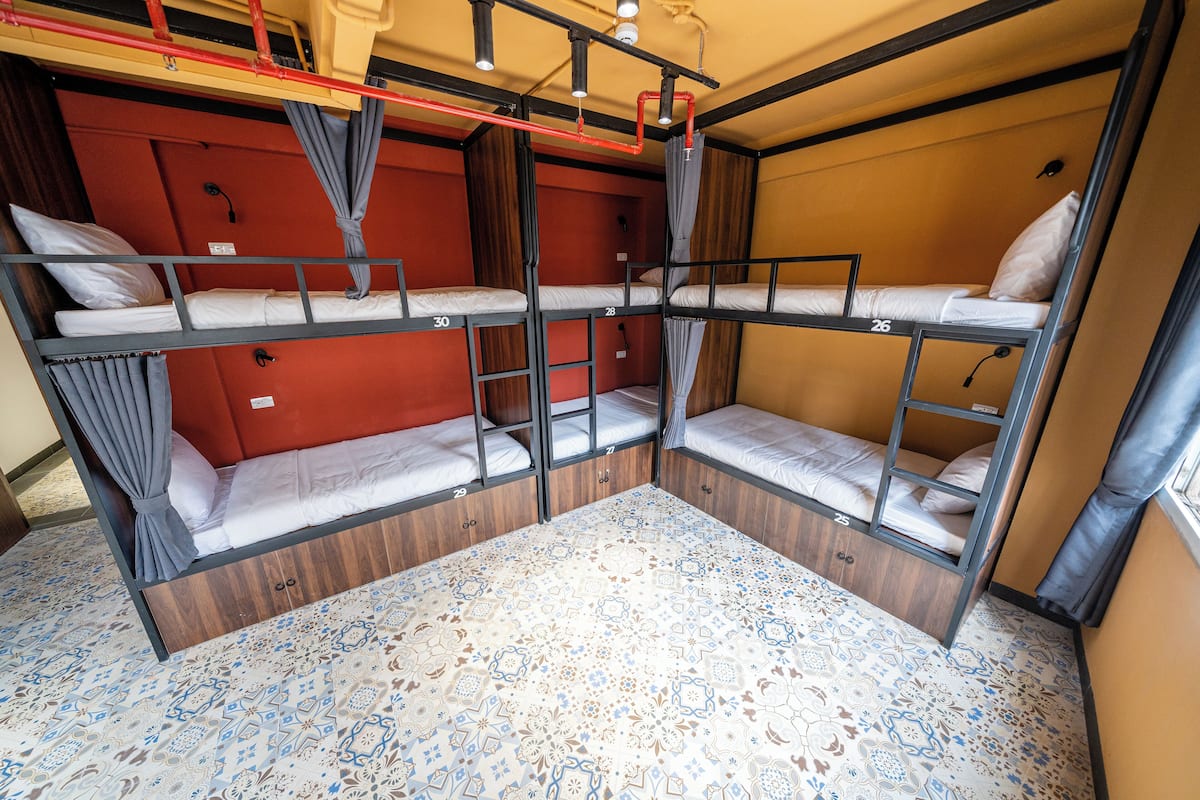 A bunk bed room with a patterned floor, wooden walls, and curtains.