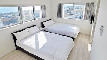 A hotel room with two beds, large windows, and a view of the city.