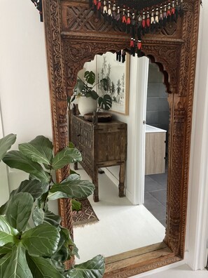 Reflect on the beauty of this serene space, featuring a stunning mirror, a wooden cabinet, and a potted plant.