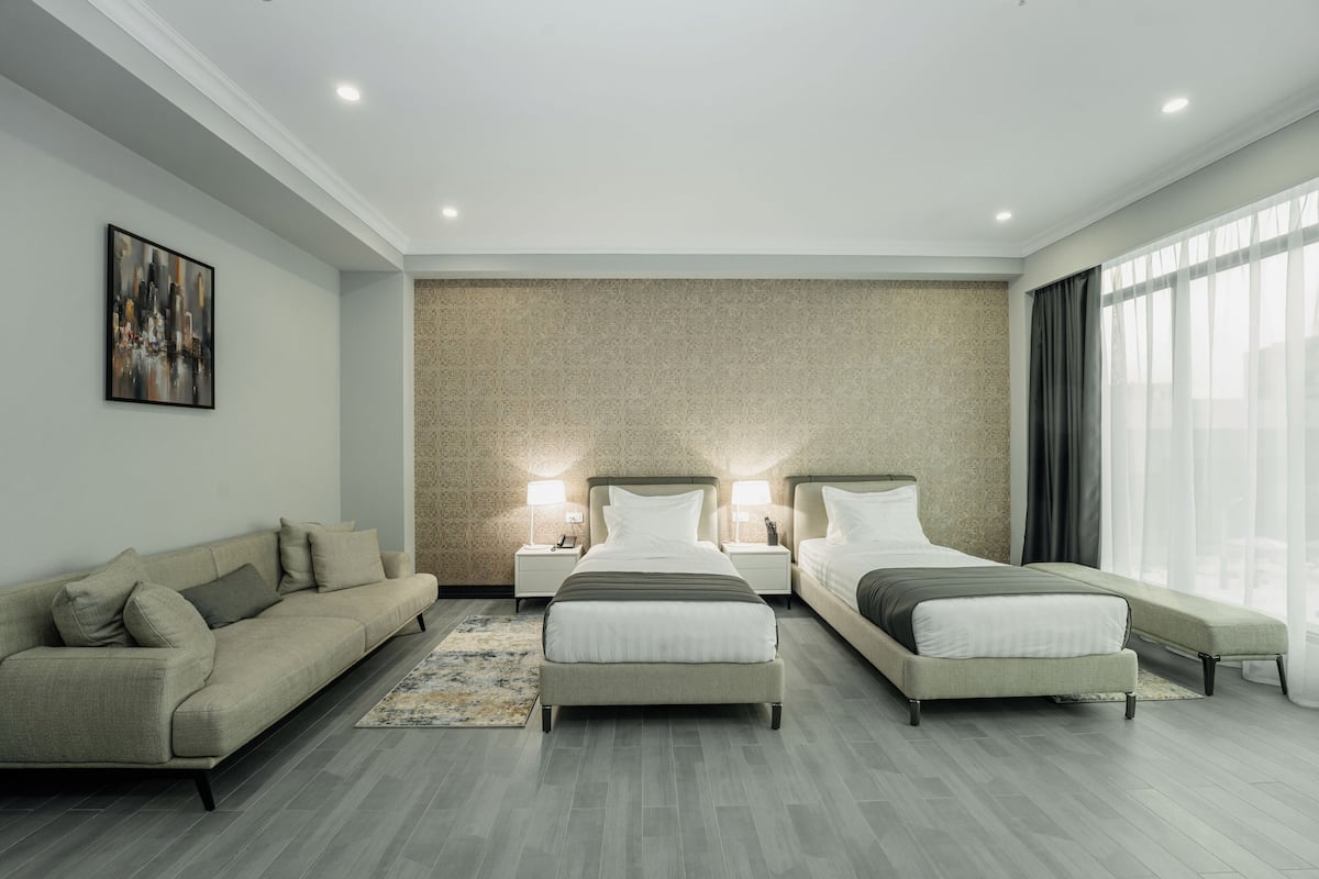 A modern hotel room with a large bed, a sofa, and a desk.