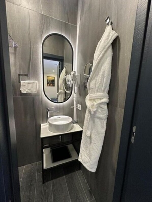 A modern bathroom with a round mirror, a white sink, and a towel rack. - Hills Resort Hotel (Yerevan)