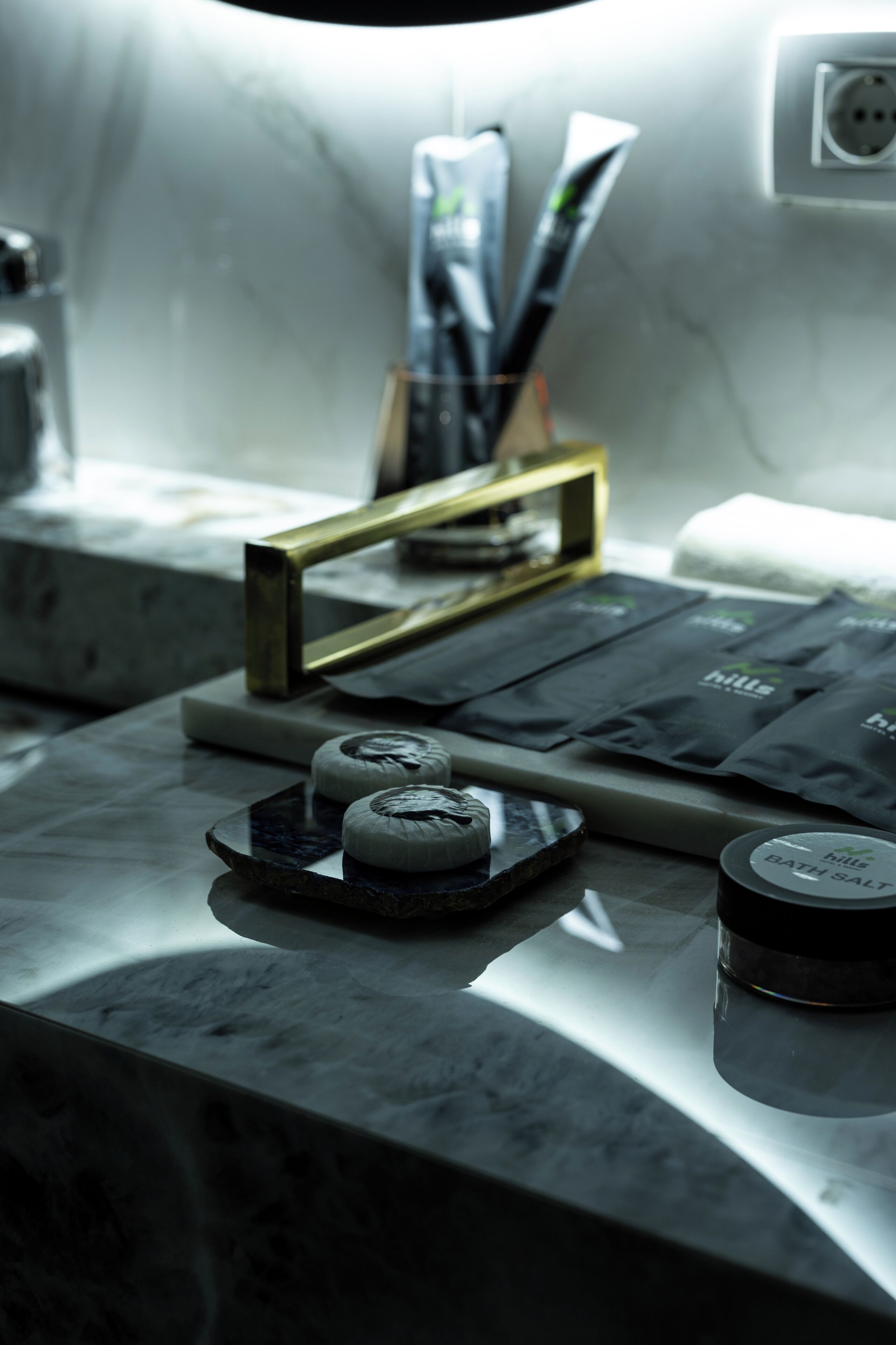 A bathroom counter with toiletries, a soap dish, and a container of bath salt.