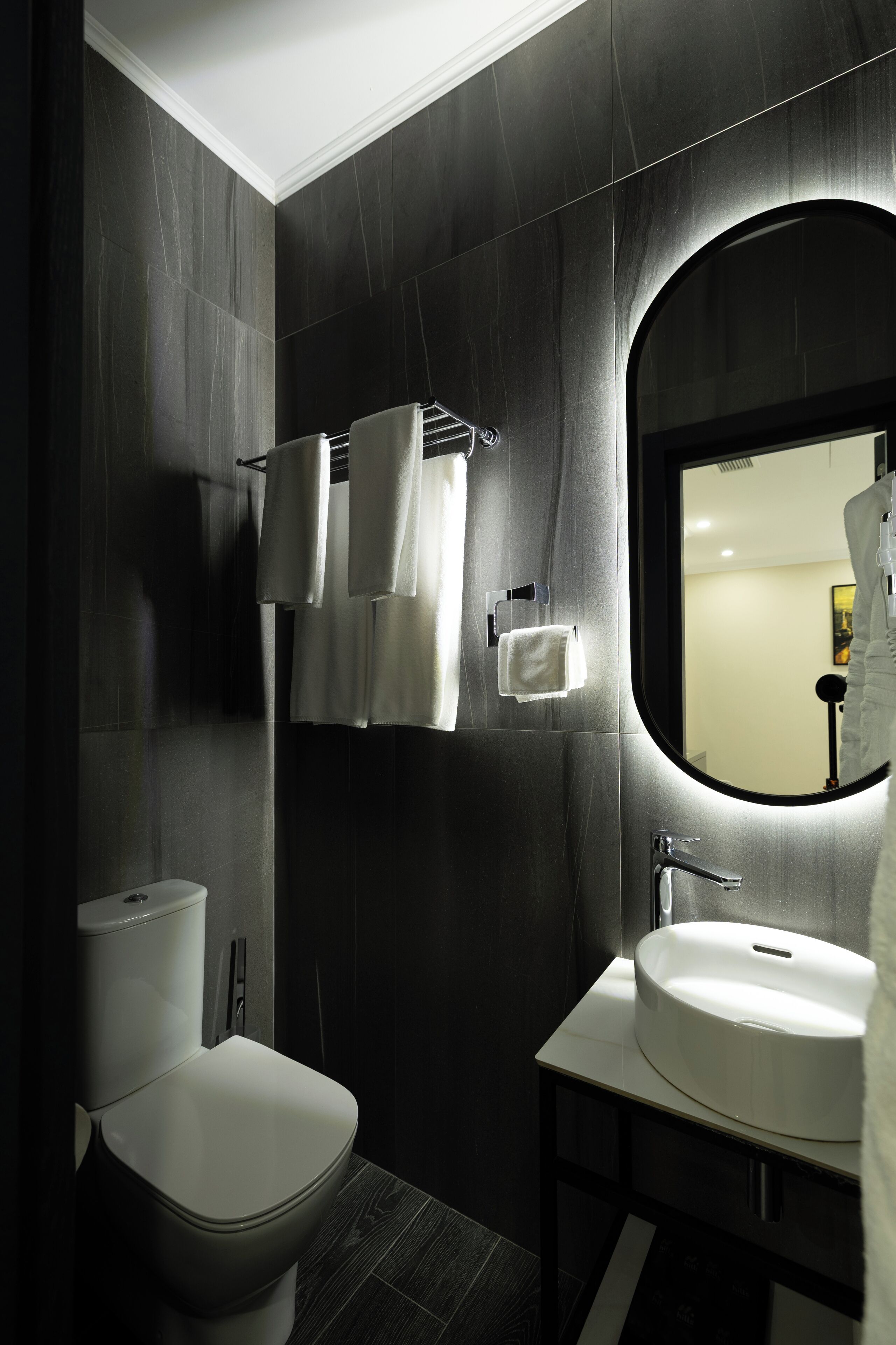 A modern bathroom with a toilet, sink, and mirror.