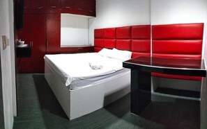 A modern room with a bed, a red upholstered headboard, a black table, and a small white bedside table. - Rapid Rise Hotel (Angeles City)