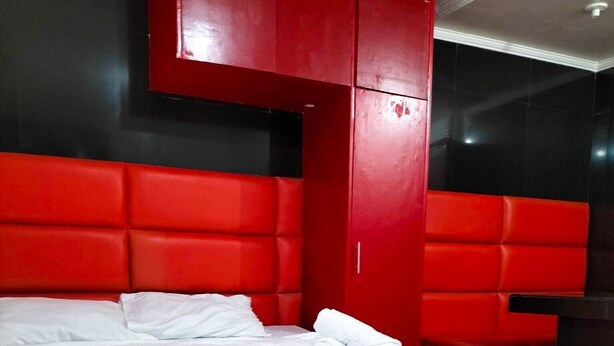 A modern hotel room with a large bed, red headboard, and black walls. - Rapid Rise Hotel (Angeles City)