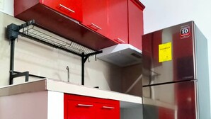 A compact kitchen with red cabinets, a stainless steel refrigerator, and a small countertop. - Rapid Rise Hotel (Angeles City)