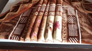 A neatly made bed with a patterned blanket and pillows, a bedside table with a glass and remote control, and a wooden headboard. - Al Marhaba Inn Hotel (Murree)
