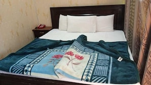 A bed with a dark headboard, white pillows, and a blue floral bedspread. - Al Marhaba Inn Hotel (Murree)