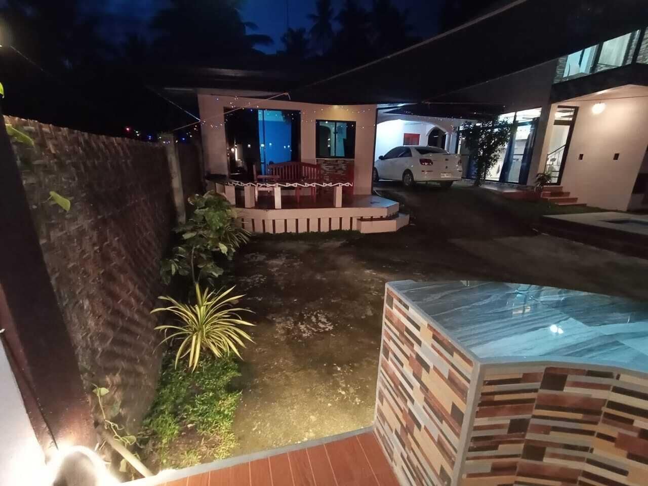 Un espacio exterior moderno con piscina, una zona de estar cubierta y un coche aparcado cerca.