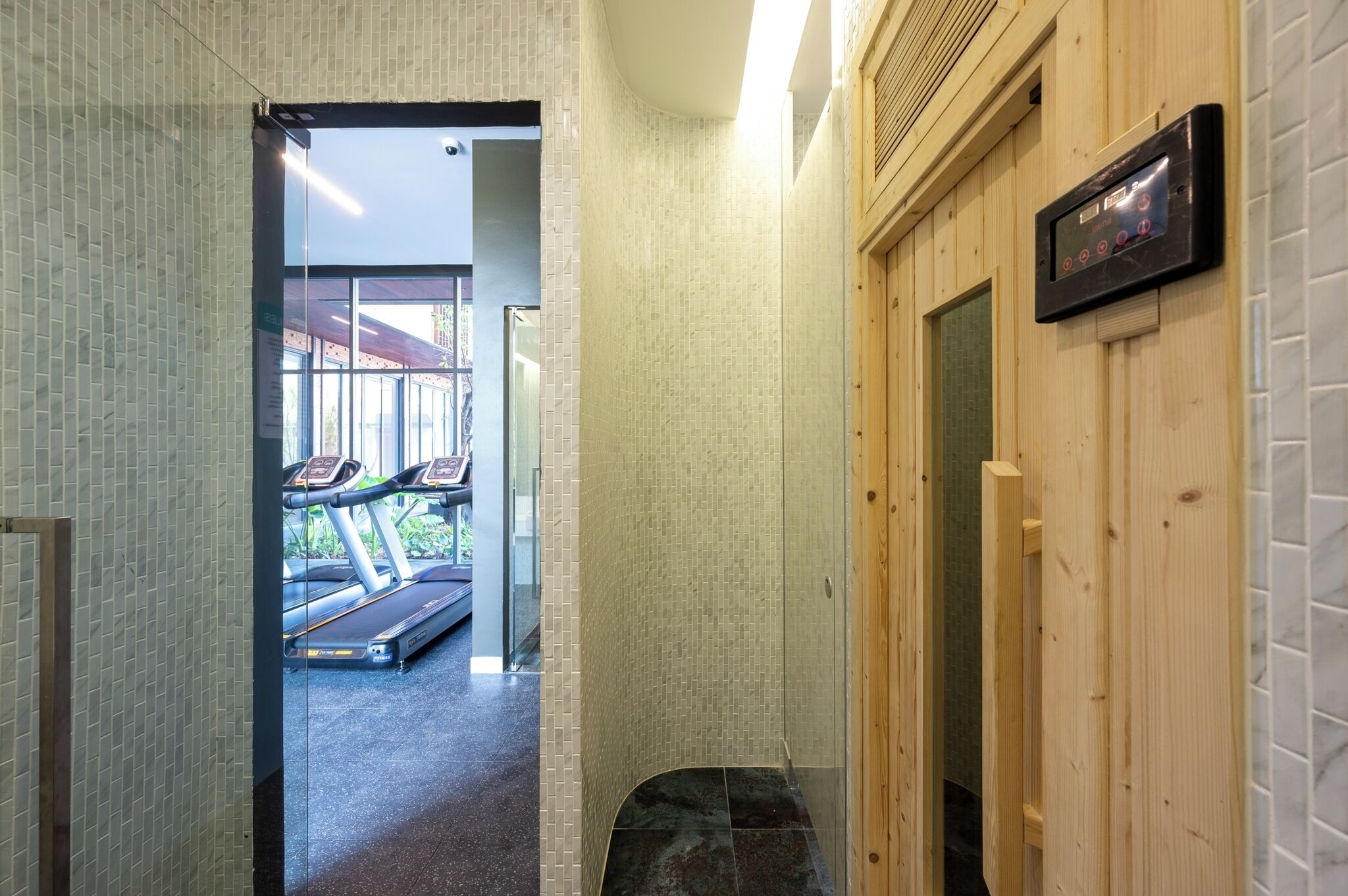 A hallway with a treadmill, wooden walls, and a tiled floor.